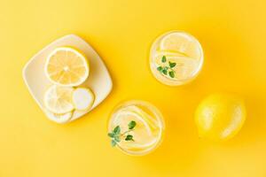 funkelnd Wasser mit Zitrone, melissa und Eis im Brille und Zitrone Scheiben auf ein Untertasse auf ein Gelb Hintergrund. alkoholisch trinken schwer Selters. oben Aussicht foto