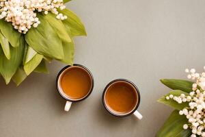 zwei Tassen mit Tee und Blumensträuße von Lilien von das Senke auf ein Grün Hintergrund. Pause zum ausruhen, schleppend Leben. oben Aussicht foto