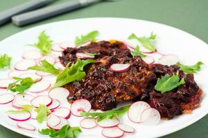 Gemüse Diät Lebensmittel. Rote Beete Steak, Rettich und Fries Salat Blätter auf ein Teller auf ein Grün Hintergrund. Nahansicht foto