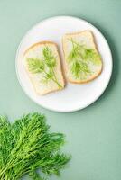 Sandwiches von Weiß Brot und frisch Dill auf ein Teller und ein Bündel von Dill auf ein Grün Hintergrund. Vitamin Kräuter im ein gesund Diät. oben und Vertikale Aussicht foto