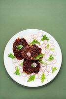 Gemüse Diät Lebensmittel. Rote Beete Steak, Rettich und Fries Salat Blätter auf ein Teller auf ein Grün Hintergrund. Vertikale Sicht, Kopieren Raum foto