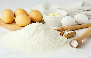 Backen Zutaten einschließlich Teig, Eier, Mehl, Zucker, und Butter mit ein rollen Stift auf ein Weiß Küche Hintergrund. foto