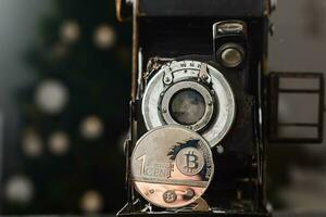 Kamera können machen Geld. Konzept von golden Bitcoin Münzen symbolisiert Elemente von virtuell Wirtschaft oder Krypto Währung und Jahrgang Film Kamera foto