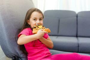 wenig Mädchen mit groß Pizza beim Zuhause foto