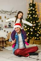 Porträt von liebend Papa mit Tochter auf seine Schultern dekorieren schön Weihnachten Baum mit Spielzeuge und Dekoration beim heim. foto