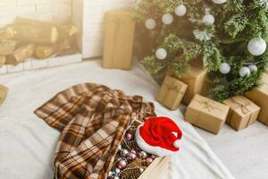 Weihnachten Geschenke in der Nähe von das Weihnachten Baum und Santa Hut foto