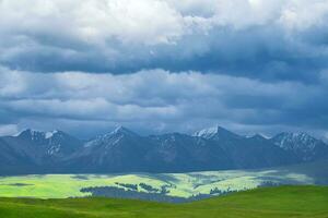 Wiese und Berge im ein wolkig Tag. Foto im kalajun Wiese im Xinjiang, China.