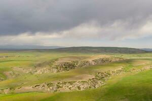 Berg Spitzen und Wiese sind unter Weiß Wolken. foto