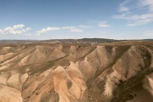 Berg Spitzen und Wiese sind unter Weiß Wolken. foto