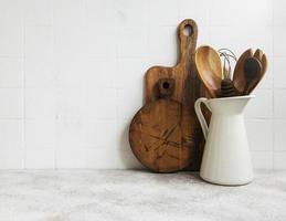 Küchenutensilien, Werkzeuge und Geschirr auf der weißen Fliesenwand im Hintergrund foto