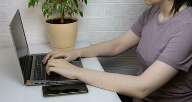 Hände Arbeiten beim ein Laptop beim ein Schreibtisch im das Büro, Nahansicht foto