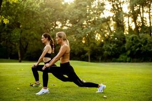 zwei ziemlich jung Frauen Dehnen im das Park foto