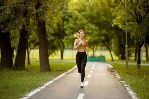 ziemlich jung Frau Laufen auf das Fahrbahn im das Park foto