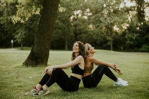 zwei ziemlich jung Frauen Sitzung auf Gras und entspannend nach draussen Ausbildung foto