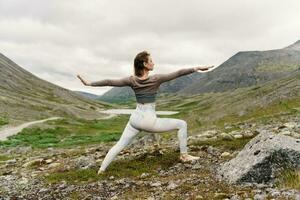 ein schlank Frau ist ein Trainer durchführen das Übung im das Berge im das Natur von das Norden. Ausbildung im komfortabel modern Sportbekleidung. schön Zahl und flexibel Körper. foto