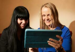 zwei jung Frau lesen ein Tablet foto
