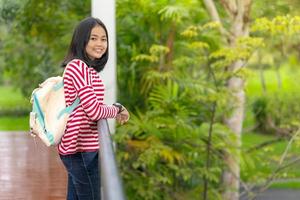 asiatisches Studentenmädchen, das an einem sonnigen Sommertag im Schulpark steht