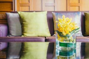 Vase Blume auf Tisch mit Kissen auf Sofa foto
