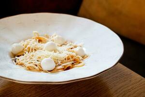 köstlich Spaghetti mit Mozarella Bälle und Tomate Soße auf hölzern Tabelle im Cafe foto
