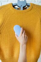 Frau im Gelb Sweatshirt mit Stoff Tabletten entfernen Werkzeug foto
