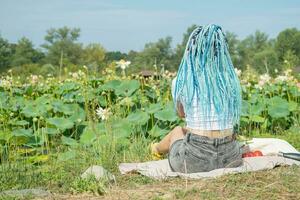 jung Frau mit schön Blau Dreadlocks ruhen auf Lotus See foto