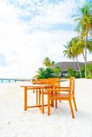 leerer holztisch und stuhl am strand mit meerblickhintergrund auf den malediven foto