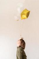 lustiger Junge, der mit Heliumballons spielt und sie auf seinem Kopf hält foto