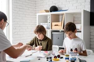 Jungen und Lehrer, die Spaß daran haben, Roboterautos in der Werkstatt zu bauen
