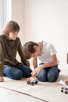 Jungen, die Spaß daran haben, Roboterautos zu bauen, die auf dem Teppich sitzen foto