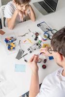 Junge und Lehrer haben Spaß beim Bauen von Roboterautos in der Werkstatt foto