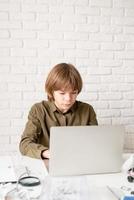 kleiner Junge, der zu Hause am Laptop arbeitet oder lernt foto