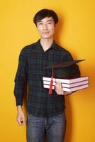 Universitätsmann ist glücklich mit Abschluss auf gelbem Hintergrund foto