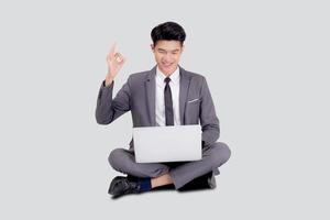 junger asiatischer Geschäftsmann, der auf Laptop-Computer sitzt, um online zu Internet isoliert auf weißem Hintergrund, Geschäftsmann selbstbewusst und Notebook, freiberuflich mit Erfolg, Marketing und Kommunikation zu arbeiten.