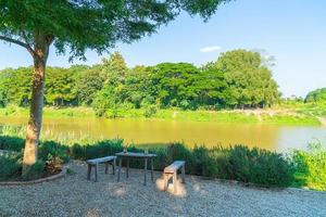 leerer Tisch und Stuhl mit Blick auf den Fluss und blauem Himmel foto