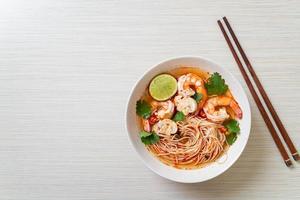 Nudeln mit scharfer Suppe und Garnelen in weißer Schüssel, oder Tom Yum Kung - asiatische Küche foto