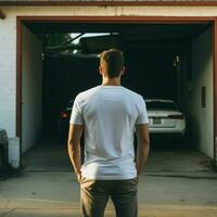 ai generativ ein Mann tragen ein einfach Weiß t - - Hemd auf das Garage gegenüber rückwärts, perfekt zu erstellen T-Shirt Attrappe, Lehrmodell, Simulation foto