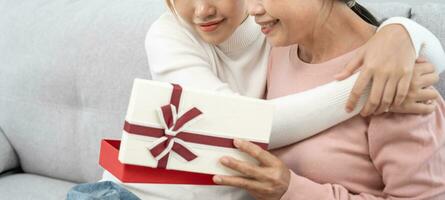 Mutter Tag, süß asiatisch Teen Mädchen geben Geschenk Box zu reifen Mitte Alter Mama. Liebe, Kuss, Pflege, glücklich Lächeln genießen Familie Zeit. feiern Besondere Gelegenheit, glücklich Geburtstag, glücklich Neu Jahre, fröhlich Weihnachten foto