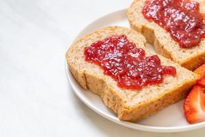 hausgemachtes Vollkornbrot mit Erdbeermarmelade und frischen Erdbeeren foto