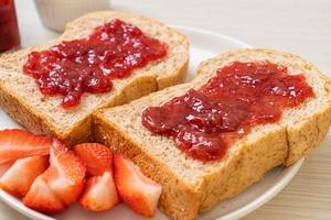 hausgemachtes Vollkornbrot mit Erdbeermarmelade und frischen Erdbeeren foto