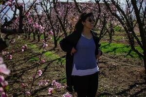 Frau Gehen durch Felder von blühen Pfirsich Bäume im Frühling. foto
