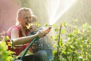 Lachen Mutter und Sohn spielen mit ein Sprinkler foto