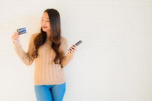 Porträt schöne junge Asiatin verwenden Handy mit Kreditkarte foto