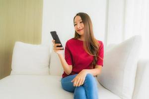 Portrait schöne junge asiatische Frauen mit Handy oder Smartphone auf dem Sofa foto