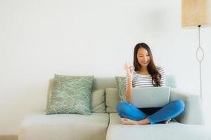 Porträt schöne junge asiatische Frauen mit Laptop oder Computer auf dem Sofa im Wohnzimmer foto