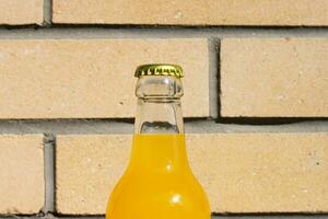 Glas Limonade Flasche gegen das Hintergrund von ein Backstein Wand.. Nahansicht Fotografie zum Banner, Förderung, Zeichnen, Poster. frisch und saftig nicht alkoholisch Sommer- trinken mit Metall Tasse. foto