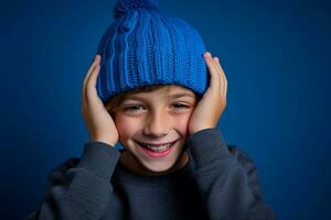 ein Junge mit ein Blau gestrickt Hut ist Lachen auf Hintergrund foto