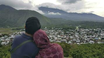 ein Mann und ein Frau suchen beim das Aussicht von das Dorf im das Berge, Sembalun, Rinjani, Indonesien foto