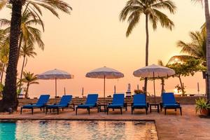 schöne Palme mit Sonnenschirmstuhlpool im Luxushotelresort bei Sonnenaufgang - Urlaubs- und Urlaubskonzept vacation