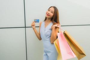 Porträt schöne junge asiatische Frau glücklich und Lächeln mit Einkaufstasche aus Kaufhaus foto