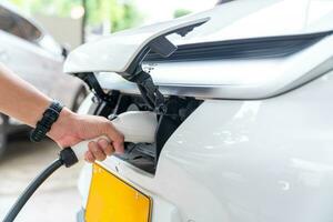 Mensch Hand Laden elektrisch Auto Batterie beim heim. elektrisch Auto Laden Bahnhof. Konzept von Grün Energie und reduzieren co2 Emission. ev Wagen. foto